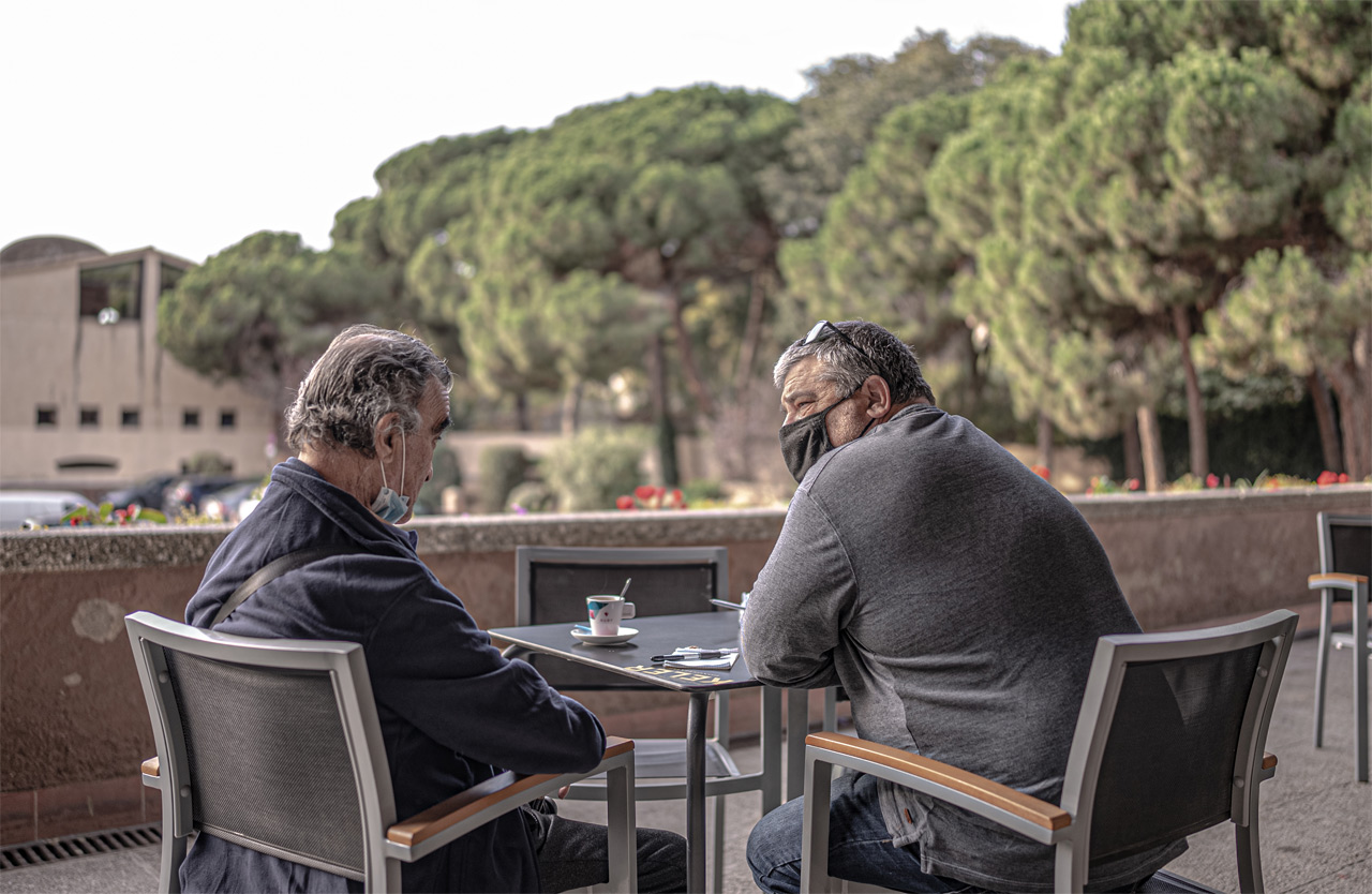 Dos hombres tomando un café en una terraza de un pueblo